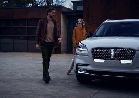A man and a woman approaching a 2024 Lincoln Aviator® SUV, which illuminates certain lights when they are close | Dorsch Lincoln in Green Bay WI
