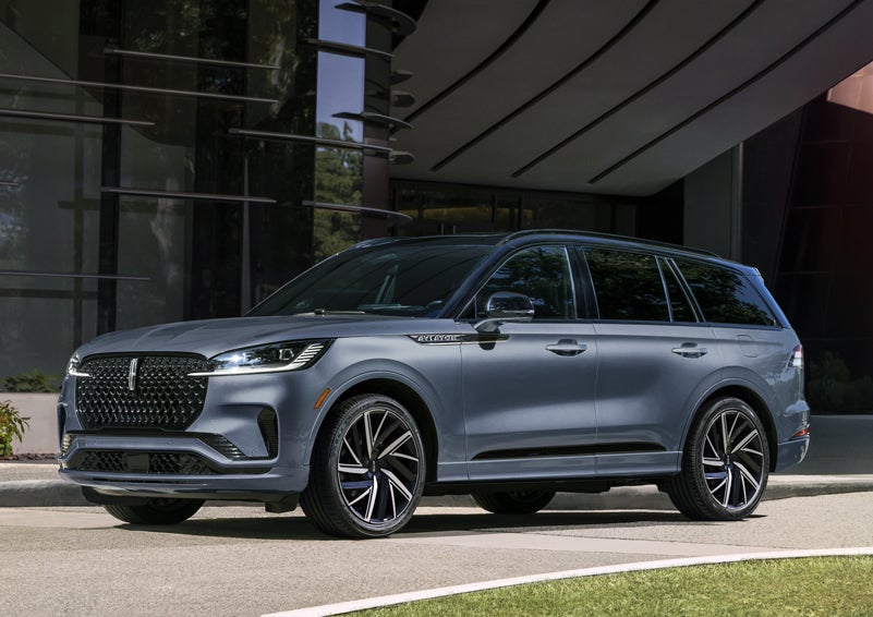 A gray 2025 Lincoln Aviator® SUV is parked outside a modern building showcasing the driver’s side of the vehicle. | Dorsch Lincoln in Green Bay WI
