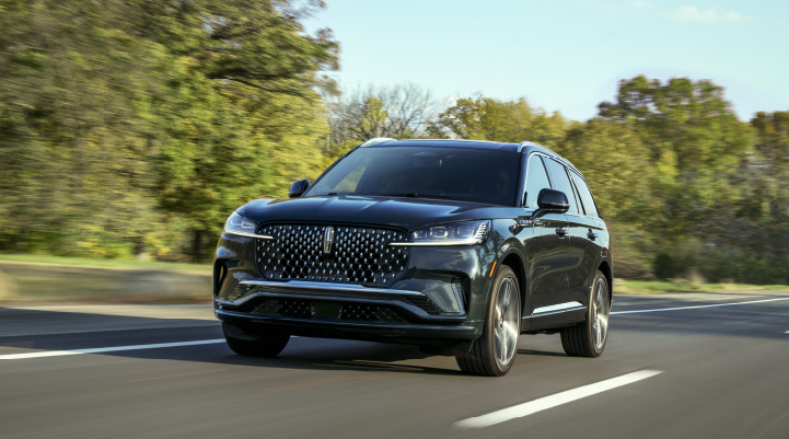 A 2025 Lincoln Black Label Aviator® SUV is being driven down a road lined with trees. | Dorsch Lincoln in Green Bay WI