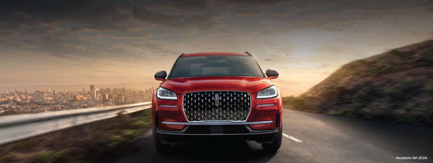 A 2025 red Lincoln Corsair® SUV is being driven down a road at sunset. | Dorsch Lincoln in Green Bay WI