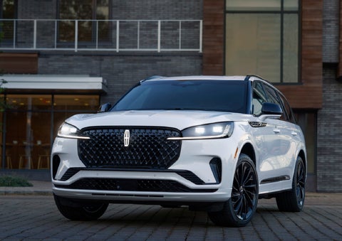 A 2026 Lincoln Aviator® Reserve model is shown with the available Jet Appearance Package parked near a restaurant. | Dorsch Lincoln in Green Bay WI