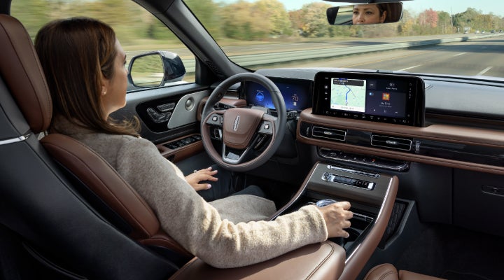 A 2026 Lincoln Aviator® SUV is being driven hands-free on a highway near a forest | Dorsch Lincoln in Green Bay WI