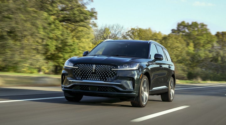 A 2026 Lincoln Black Label™ Aviator® SUV is being driven down a road lined with trees. | Dorsch Lincoln in Green Bay WI