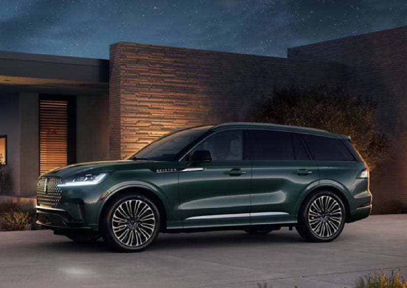 A green 2027 Lincoln Aviator® SUV is parked outside a contemporary home. | Dorsch Lincoln in Green Bay WI