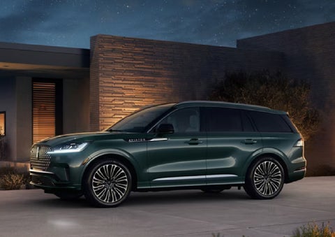 A green 2027 Lincoln Aviator® SUV is parked outside a contemporary home. | Dorsch Lincoln in Green Bay WI