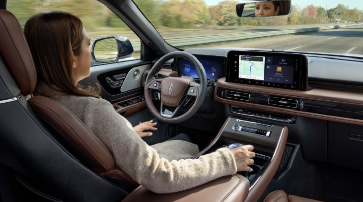 A 2027 Lincoln Aviator® SUV is being driven hands-free on a highway lined with trees. | Dorsch Lincoln in Green Bay WI