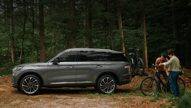 A father and son load e-bikes on a bike rack attached to a 2027 Lincoln Aviator® SUV. | Dorsch Lincoln in Green Bay WI